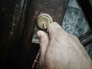 Mano abriendo cerradura antigua oxidada