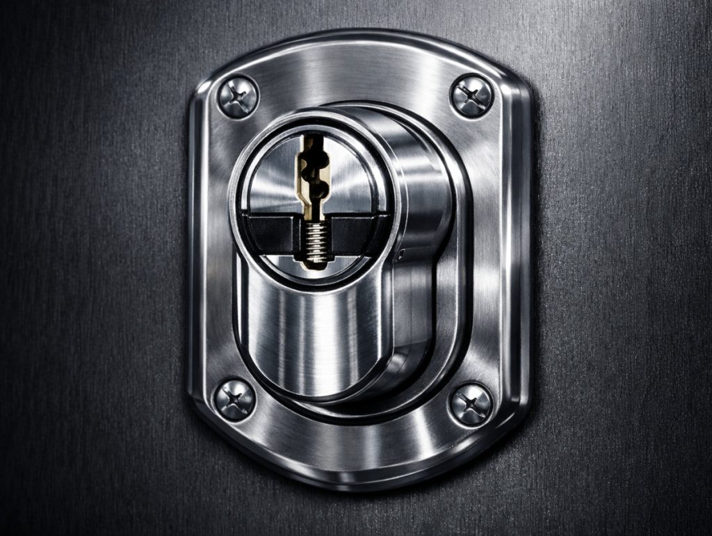 Primer plano de cilindro de cerradura de alta seguridad SKG 3 estrellas con escudo acorazado Disec instalado en puerta blindada moderna, sistema de protección contra bumping y rotura utilizado por Cerrajería Novoa en Vigo